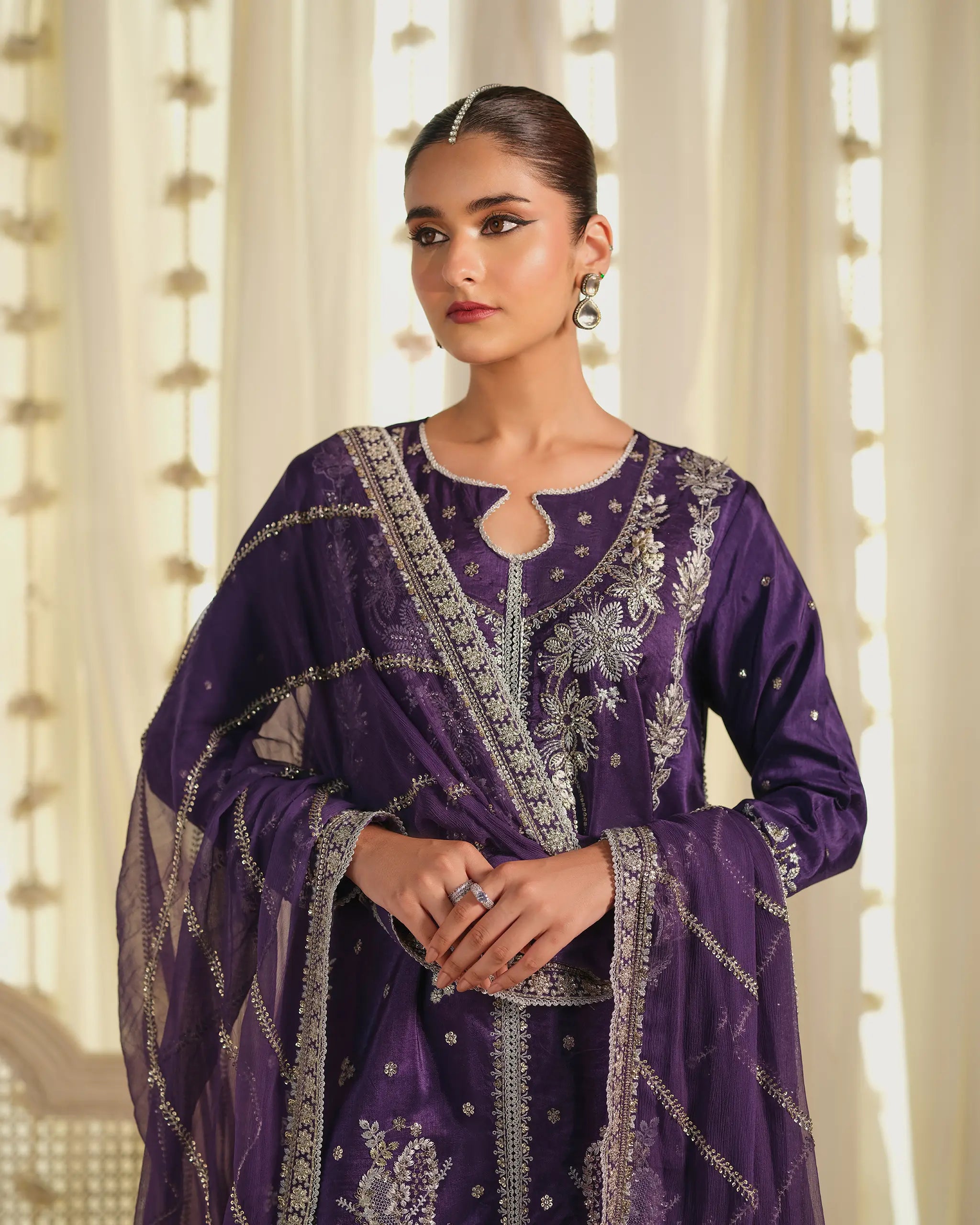 Close-up of the model wearing the purple 'Khumaar﻿' suit, highlighting the intricate silver embroidery on the neckline and the sheer, embellished 'dupatta﻿'.