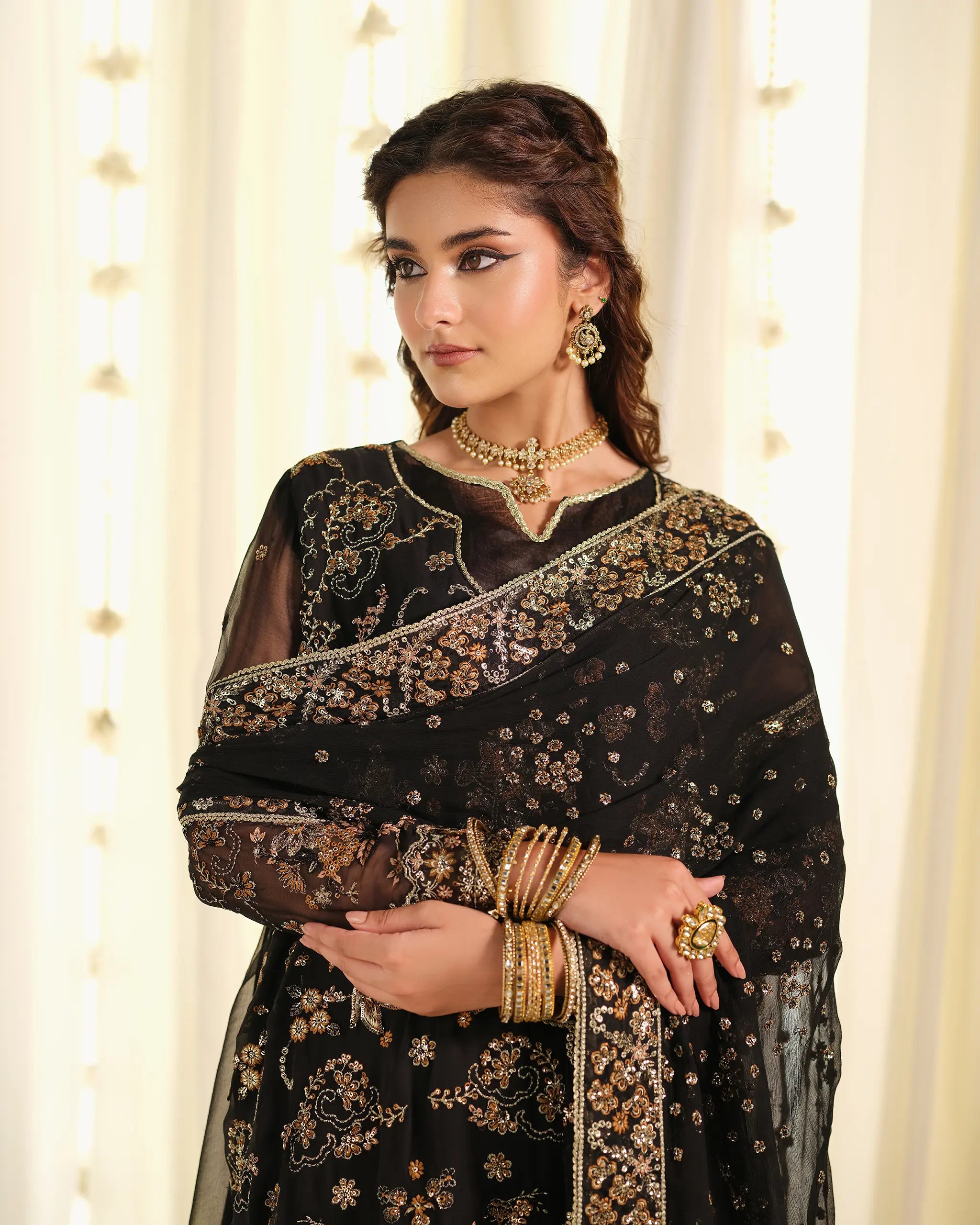 Close-up of a model wearing the black 'Mahtaab﻿' outfit, styled with a gold choker, matching earrings, and stacked bangles, highlighting the festive look.