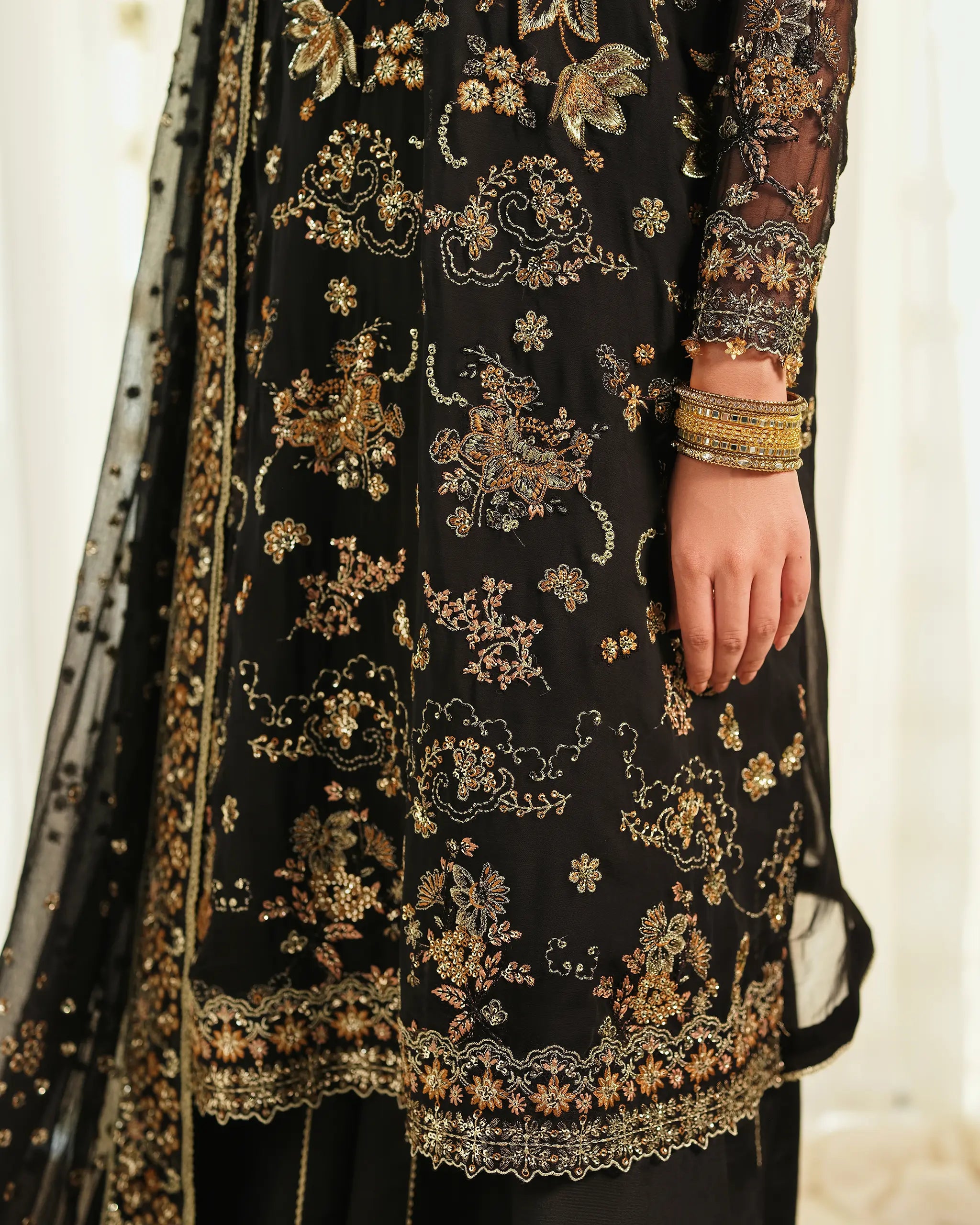 Detailed shot of  'Mahtaab﻿' the black  suit from the 'Pehla Khat' set, focusing on the dense gold and silver floral embroidery and sequin work.
