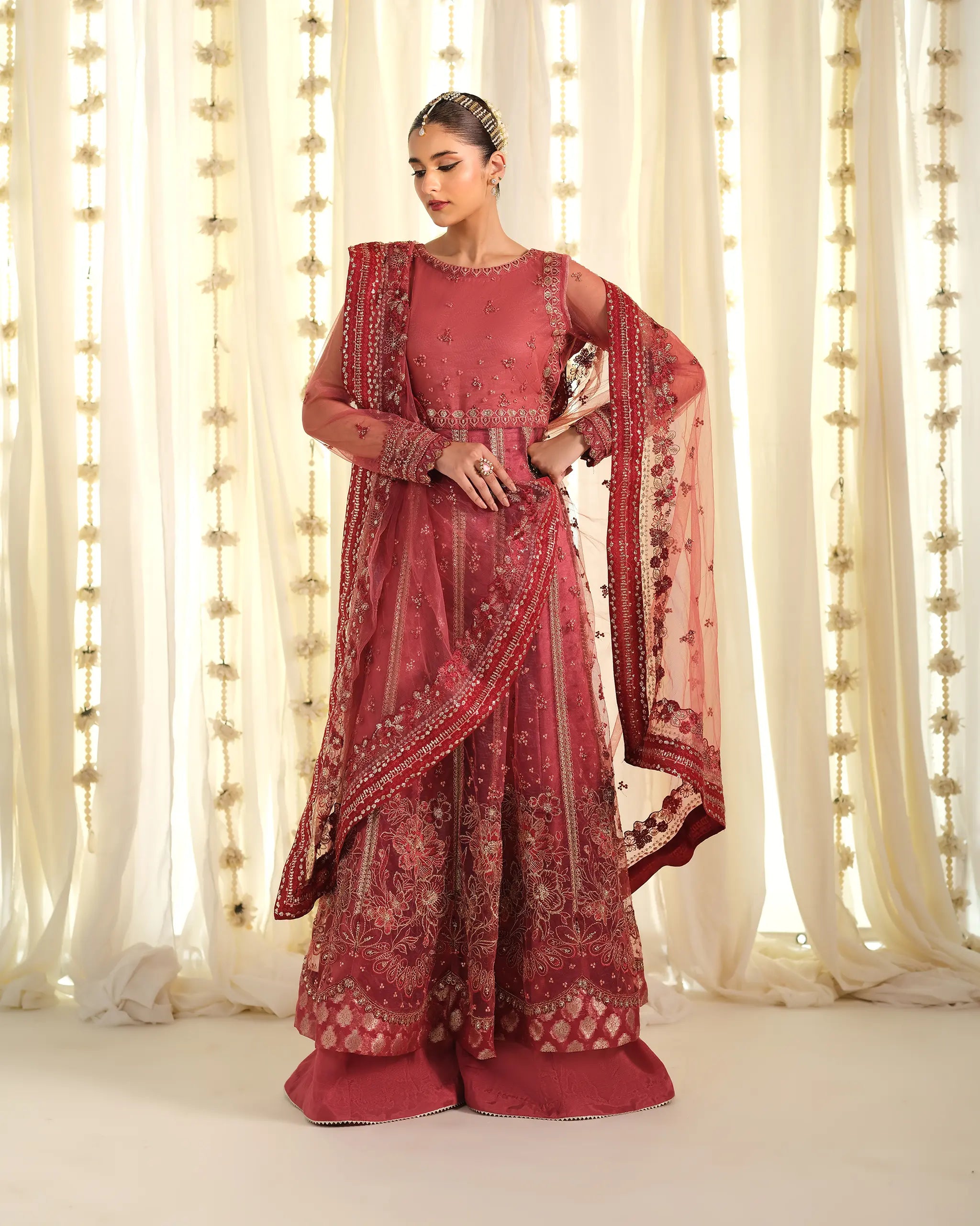 Model looking down while showcasing a heavily embroidered dusty pink suit 'mohabbat' with a sheer, embellished dupatta﻿ from the 'Pehla Khat' collection.
