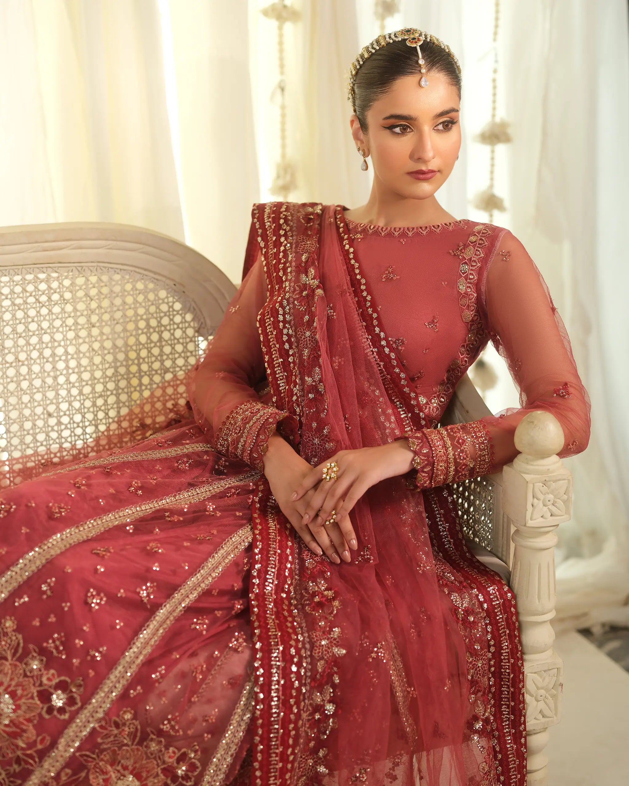 Close-up of a model seated gracefully in the dusty pink 'Mohabbat﻿' outfit, highlighting the intricate beadwork on the bodice and traditional hair jewelry.