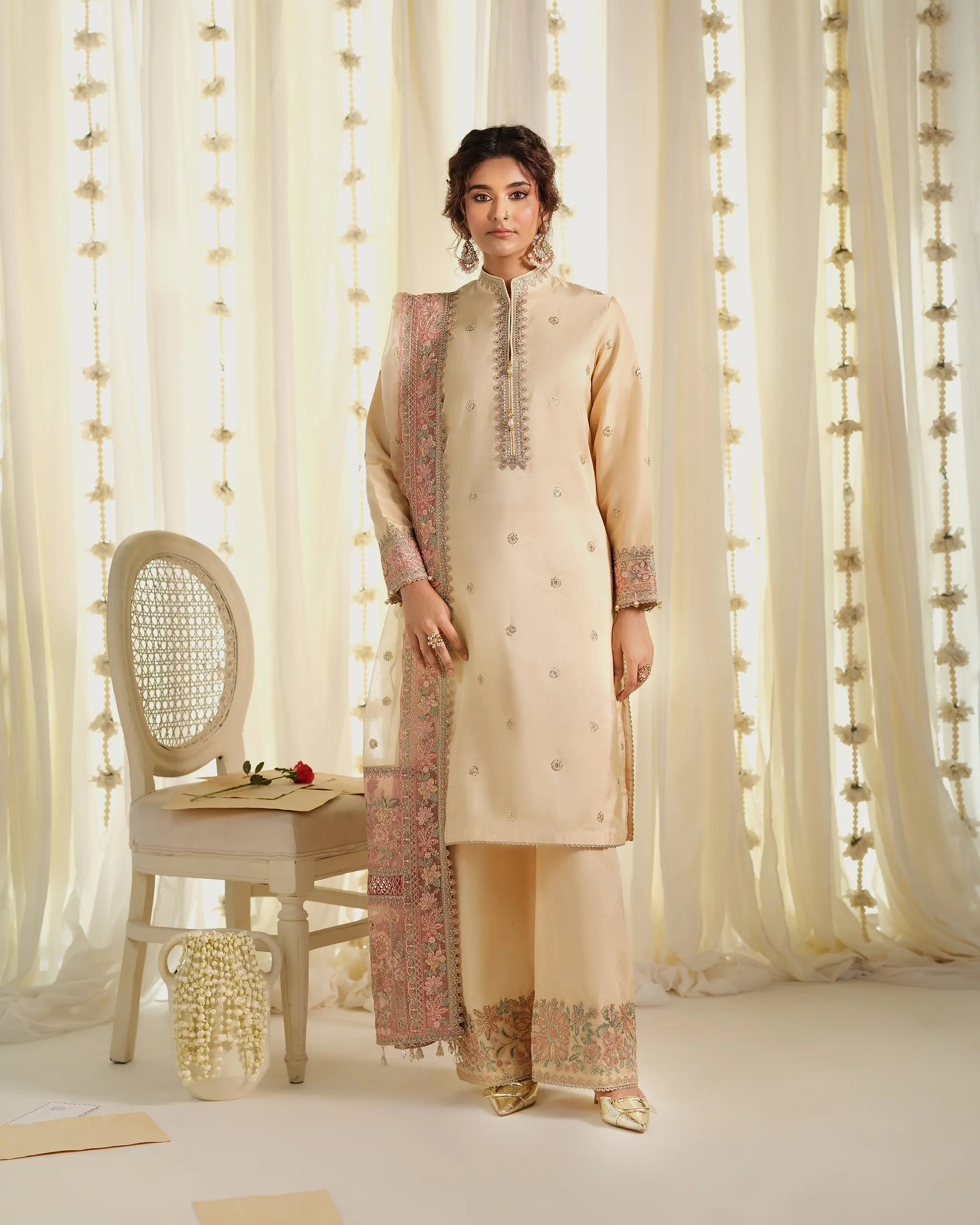 A full-length view of a model in a suit with embroidered shalwar and a contrasting pink organza dupatta﻿ from the 'Pehla Khat﻿' collection.