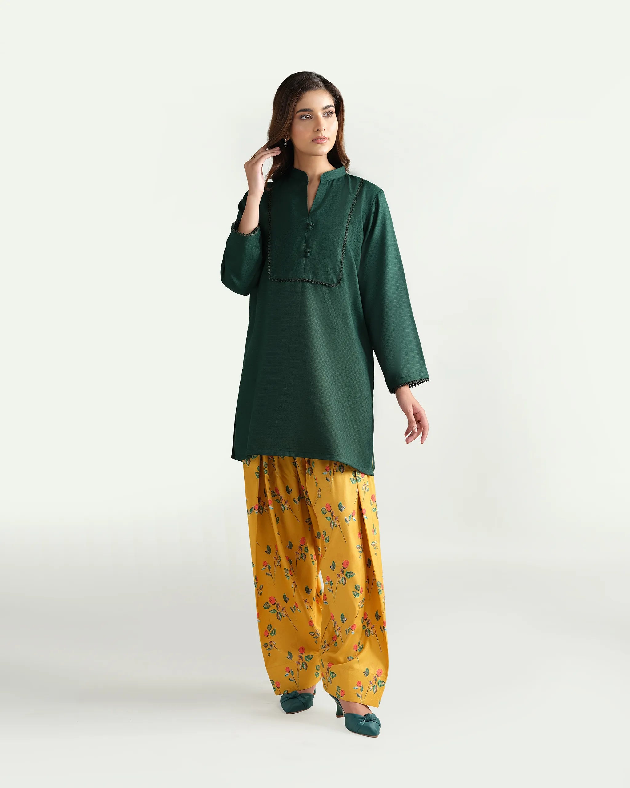 Sinoor's 'Nora' pret suit from the Winter Basic Collection. Features a dark green kurta paired with a vibrant yellow floral shalwar. Ready-to-wear for women.