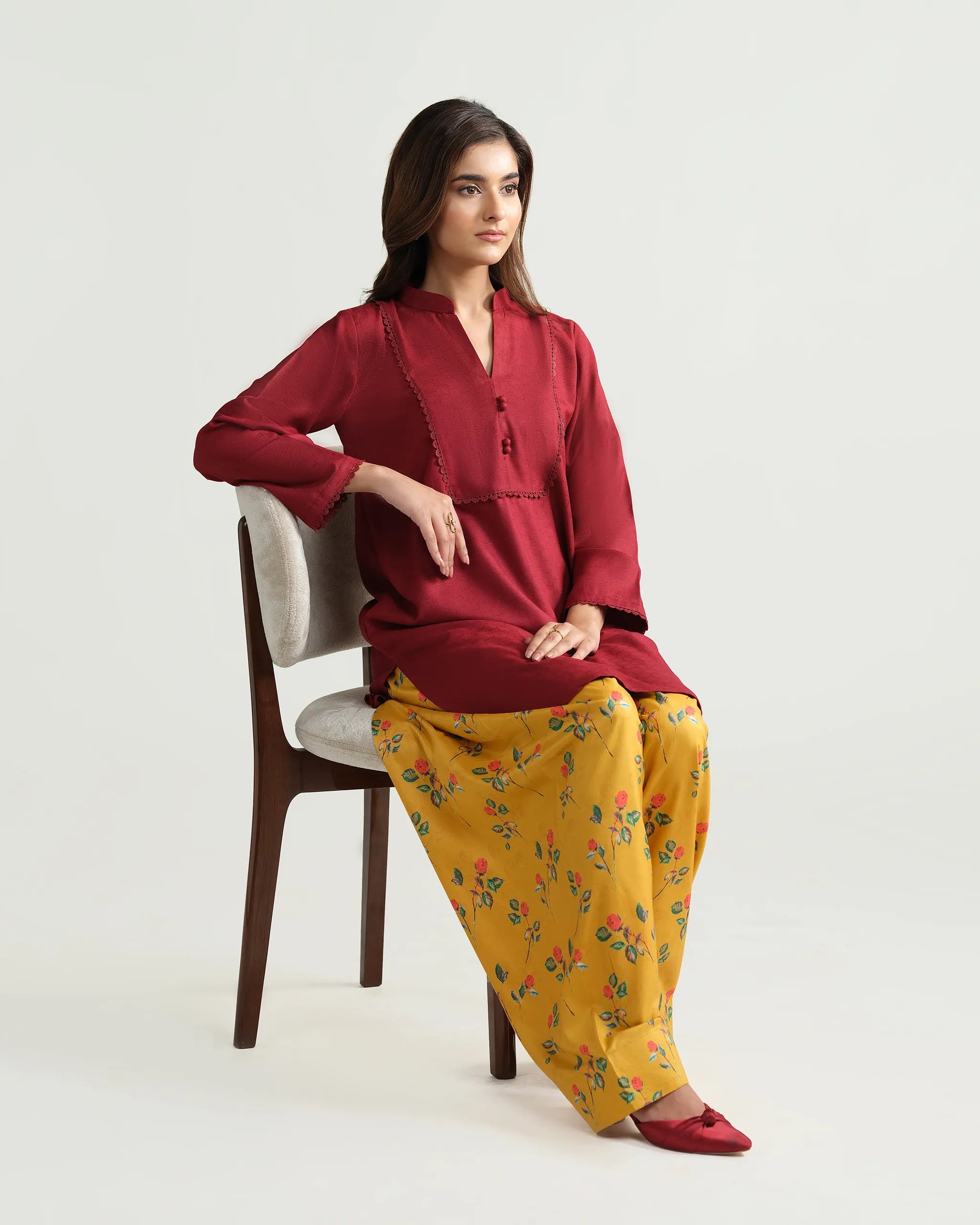 Sinoor's 'Nora' pret suit from the Winter Basic Collection, pairing a red kurta with a yellow floral shalwar. Stylish ready-to-wear for women.