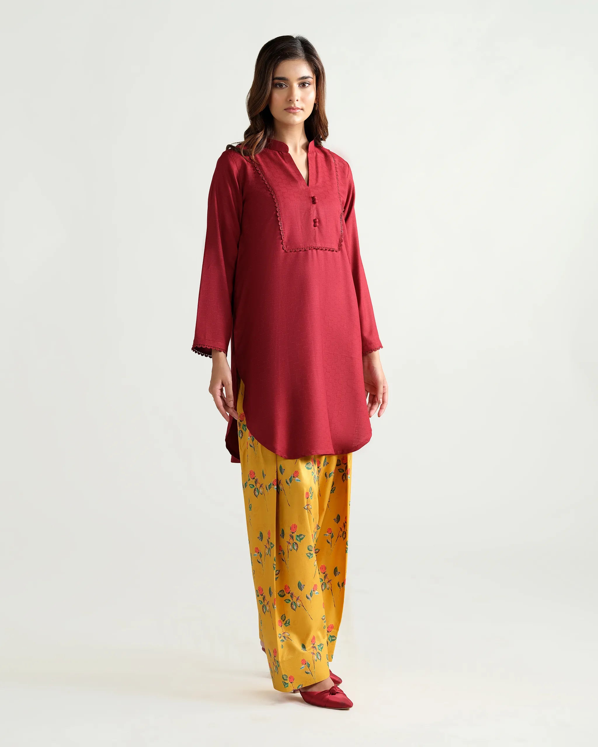 Sinoor's 'Nora' pret suit from the Winter Basic Collection, pairing a red kurta with a yellow floral shalwar. Stylish ready-to-wear for women.
